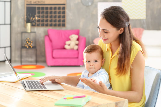 Woman with baby on lap, looking through Montessori blogs.