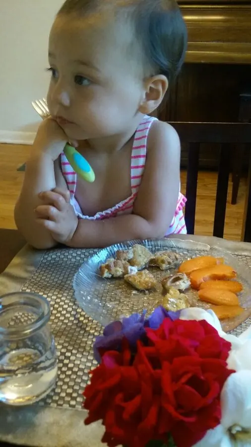 child sitting at Montessori weaning table eating.