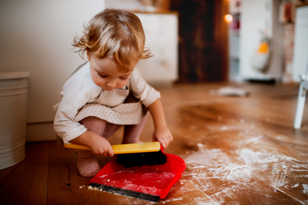 child sweeping up flour from floor as part of natural and logical consequences.