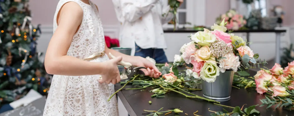 child cutting flower stems for flower arrangement.