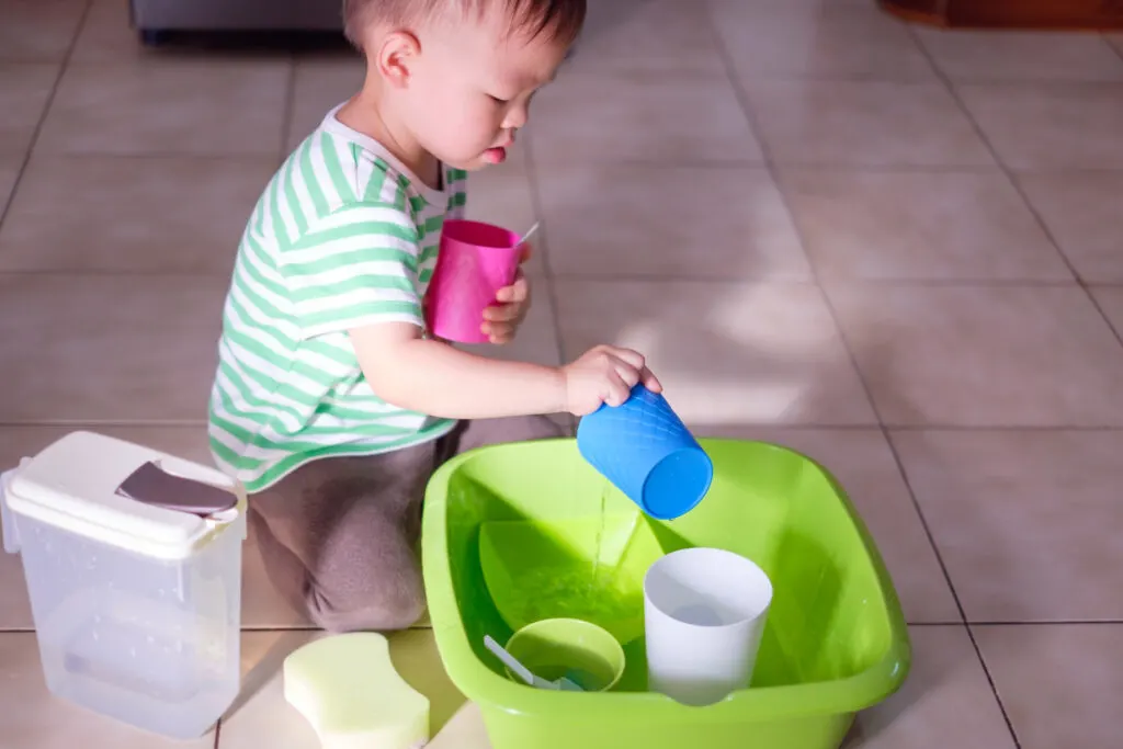 child washing dishes as a practical life activity for Montessori on a budget.