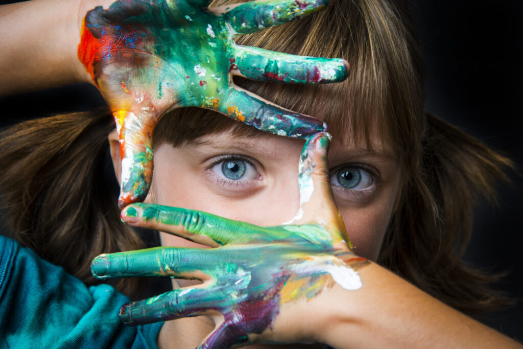 child being creative with paint on her hands.