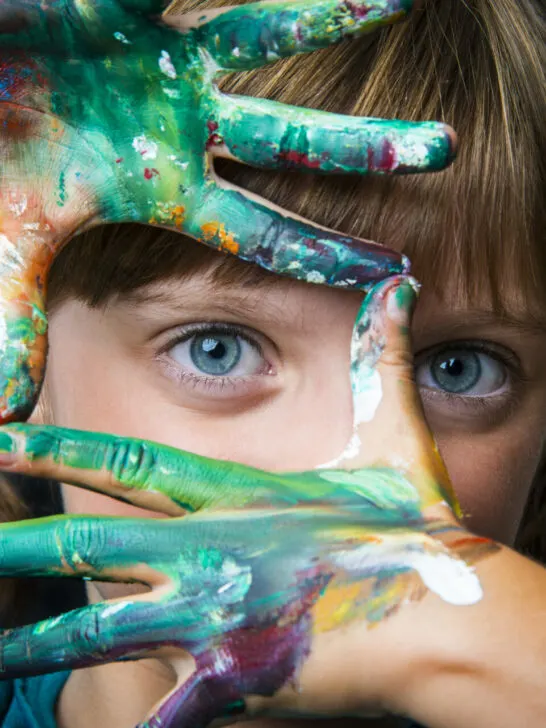 child being creative with paint on her hands.