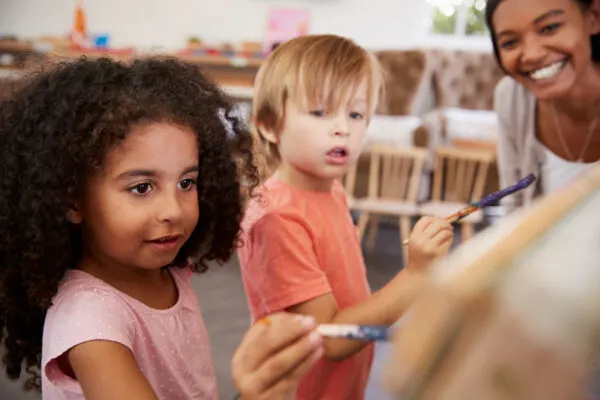 good montessori teacher watching children paint.