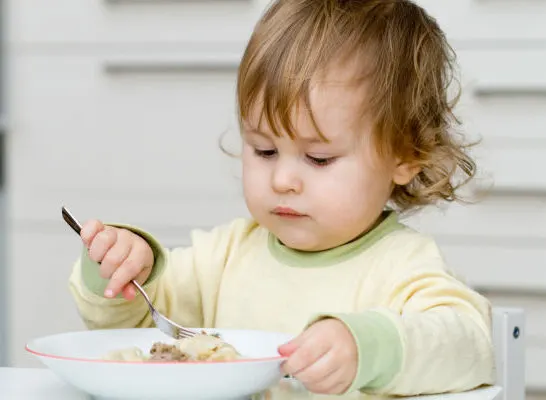 child eating with real dishes at montessori weaning table.