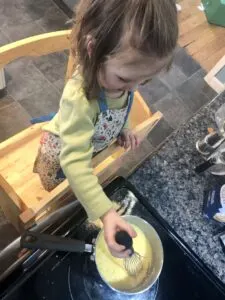 Toddler mixing cornmeal on stove for Fry Bread.