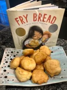 Cooked fry bread on tray with Fry Bread book behind it.