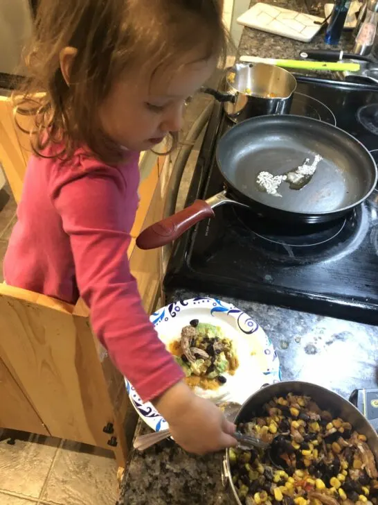 Toddler assembling her quesadillas for fun cooking activities for toddlers inspired by books.