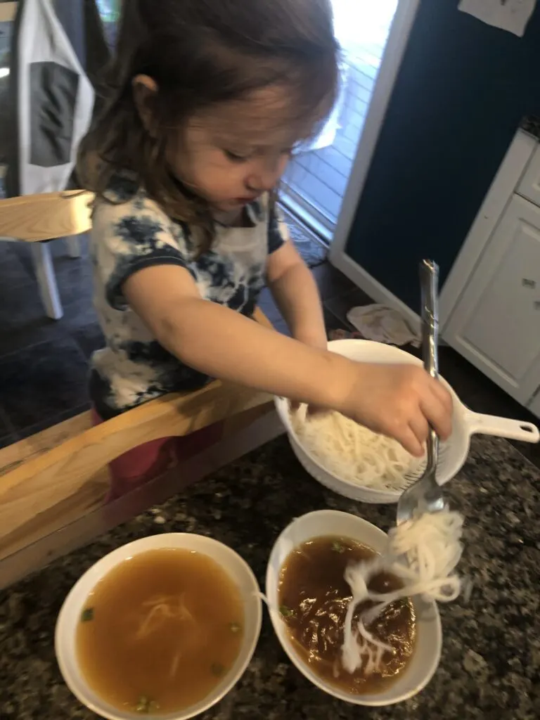 Cooking activities for toddlers: girl putting Noodles in wonton soup for dim sum.