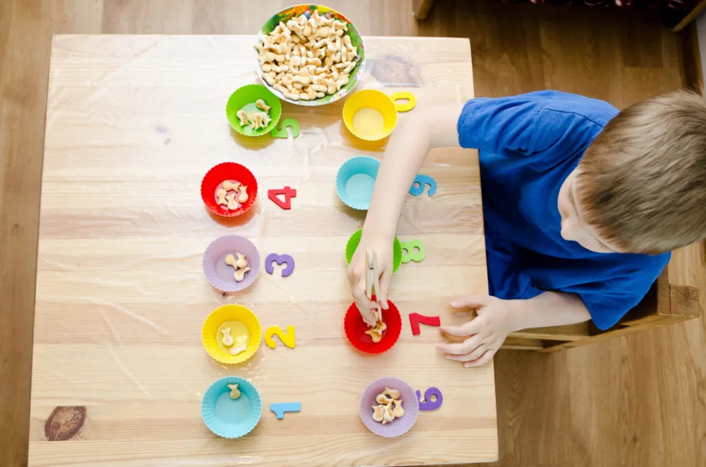 child using Godlfish crackers for Montessori math activity.