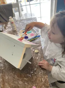 toddler painting diy wooden birdhouse with father.