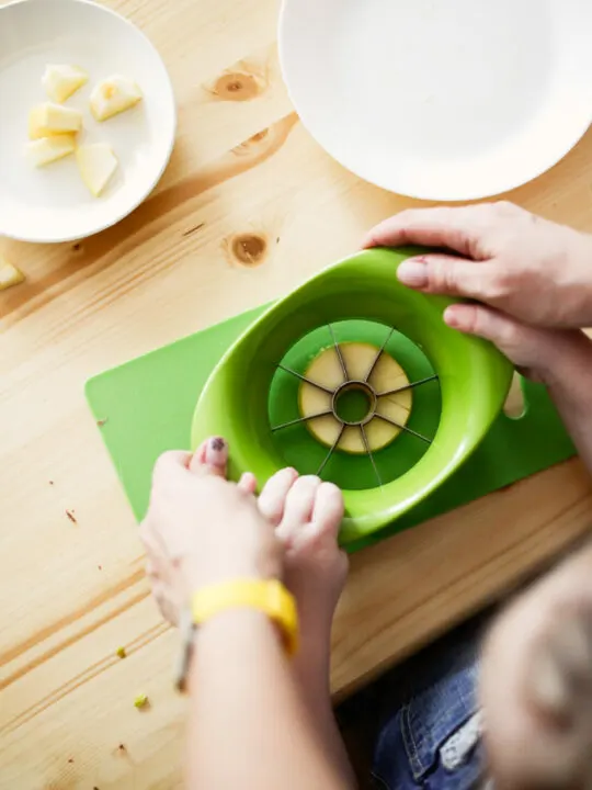 image of child cutting an apple when doing Montessori at home.
