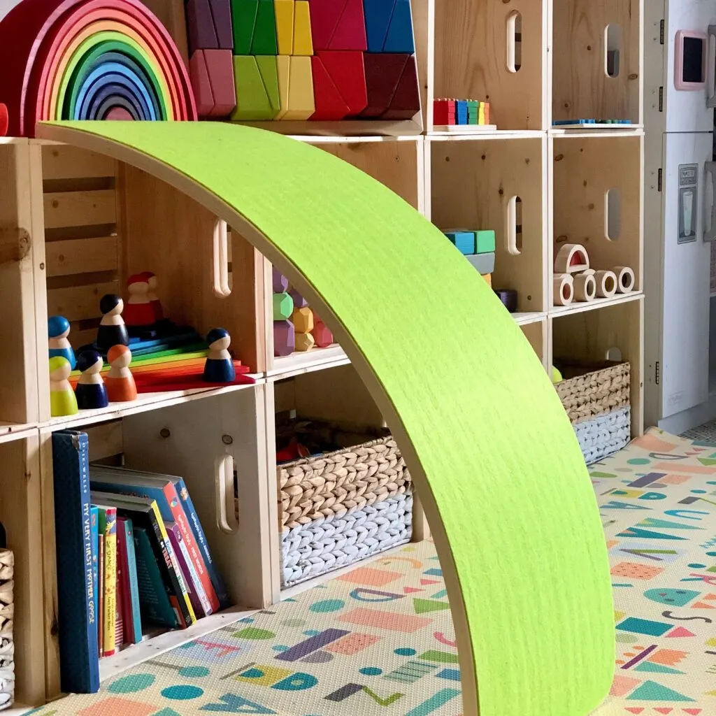 image of green walnut balance board. against toy shelf.