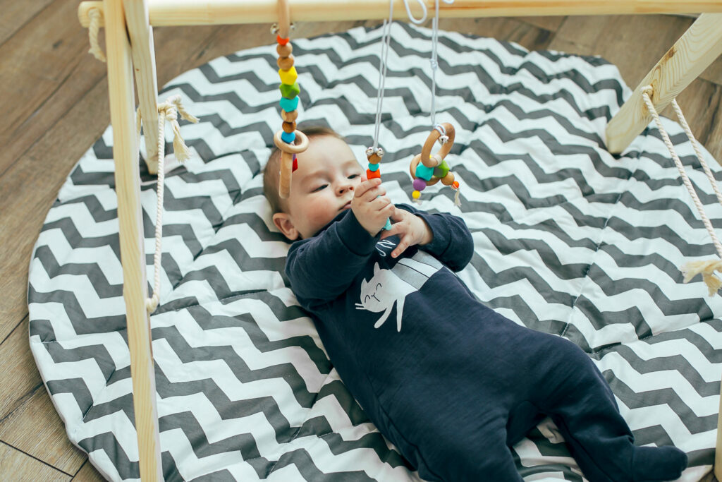 image of baby engaging with wooden play gym toys.