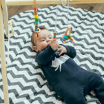 image of baby engaging with wooden play gym toys.