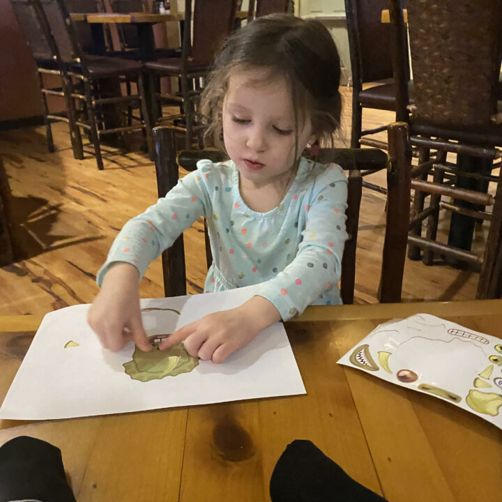 child playing with stickers at a restaurant. Stickers are one of the great toys for restaurants. 