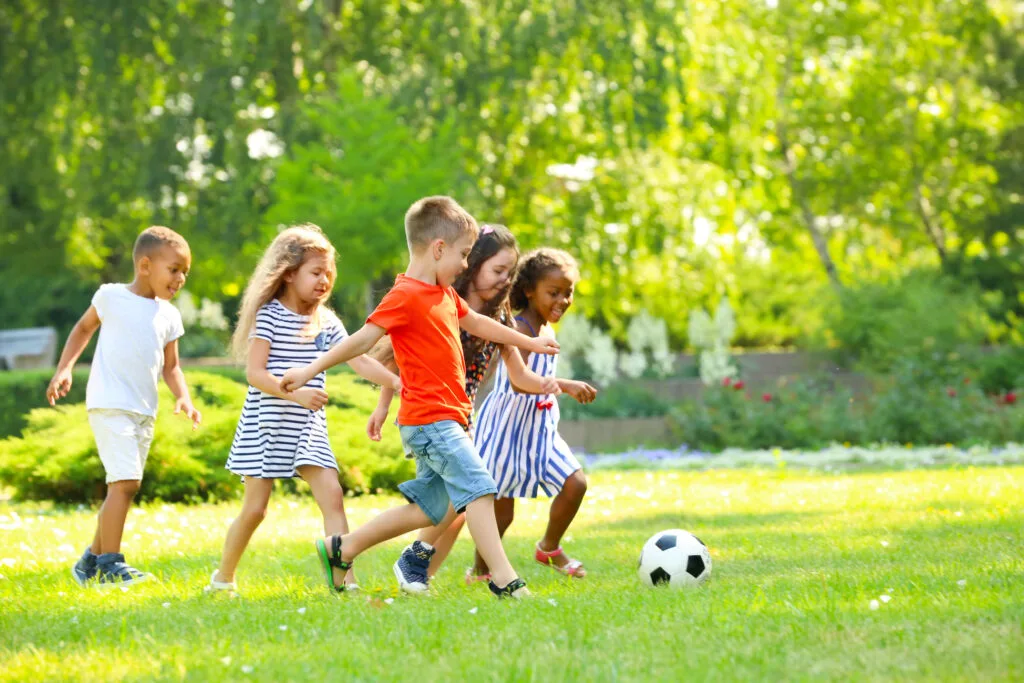 young children playing soccer together, demonstrating cooperative play, one of the 6 stages of play.