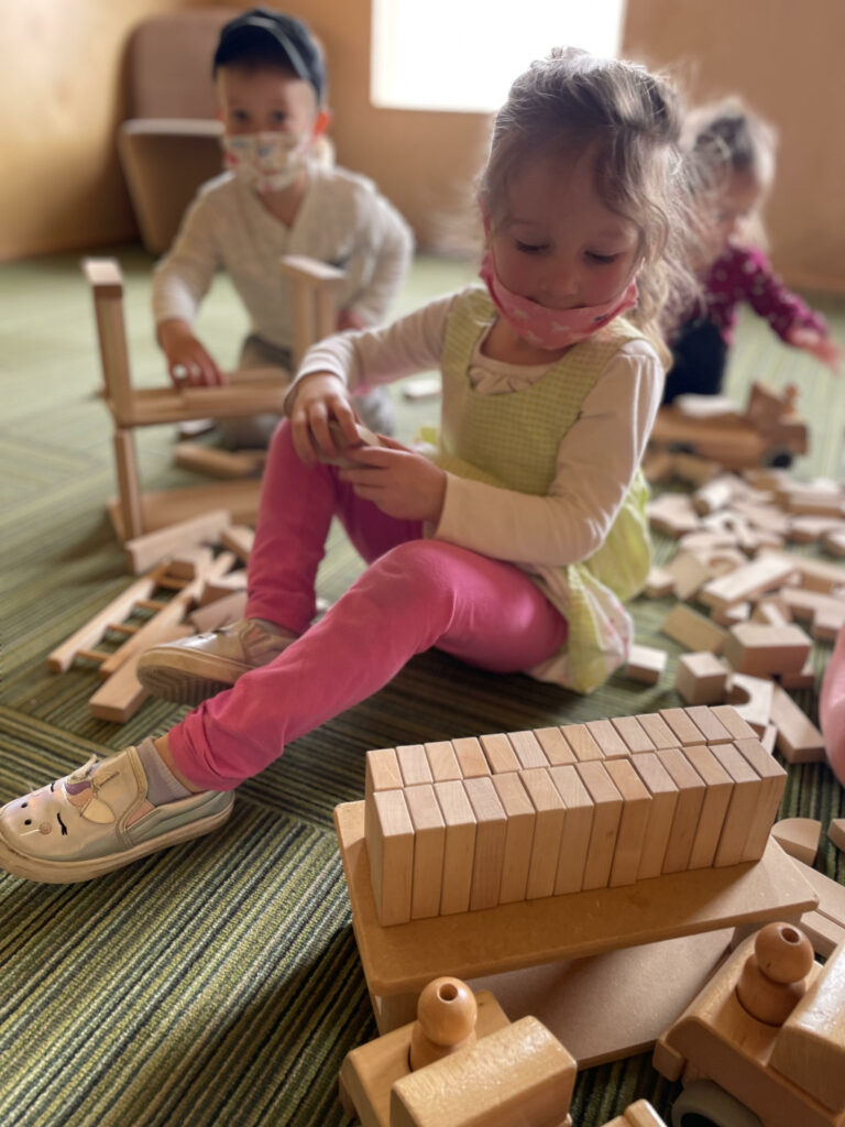 young children demonstrating associative play while building with wooden blocks.