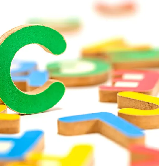 Image of randomly colored toys, including the letter c, which is standing.