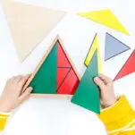 Image of child working with green, blue, anf yellow Montessori Constructive triangles.