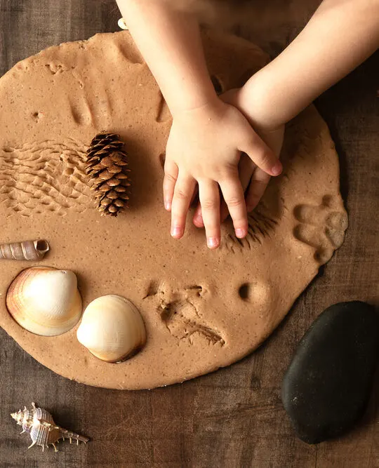 Image of child making sand impressions at a Montessori nature table.