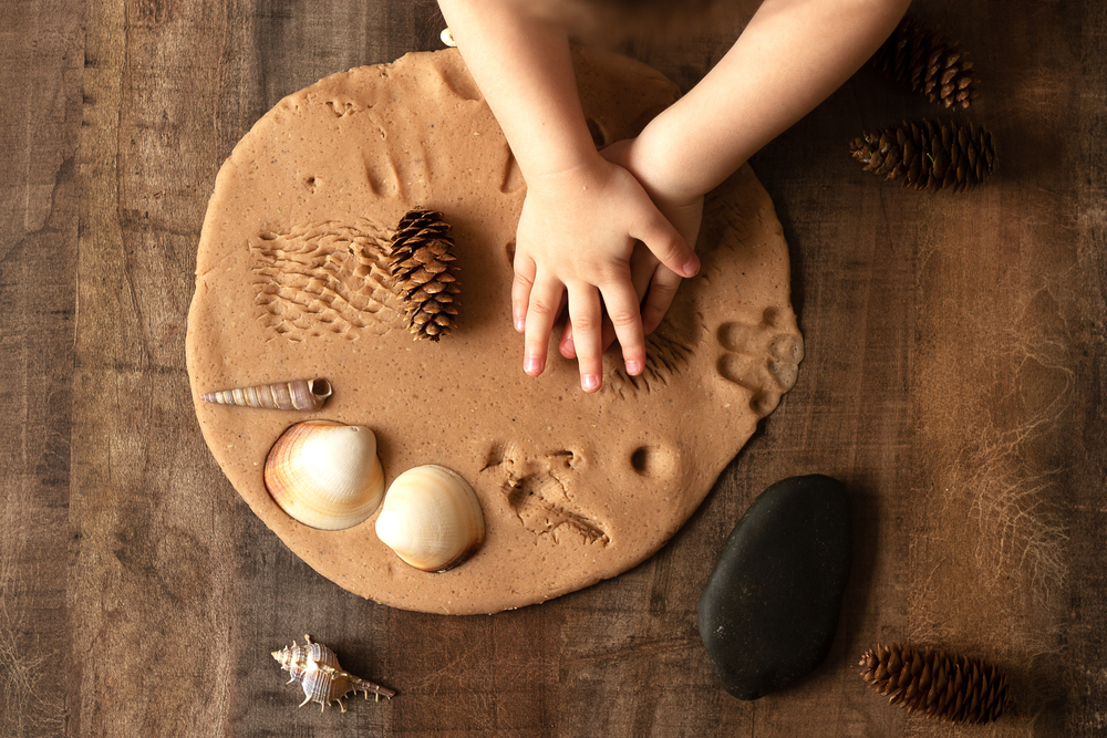 Image of child making sand impressions at a Montessori nature table.