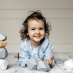 Image of smiling child playing with neutral color Montessori balancing stones.