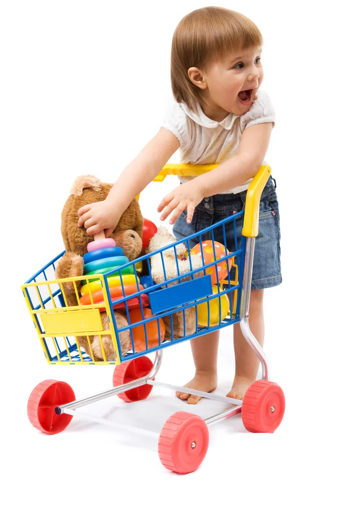 image of a young child putting toys in a shopping cart, which shopping carts are transportation schema toys.