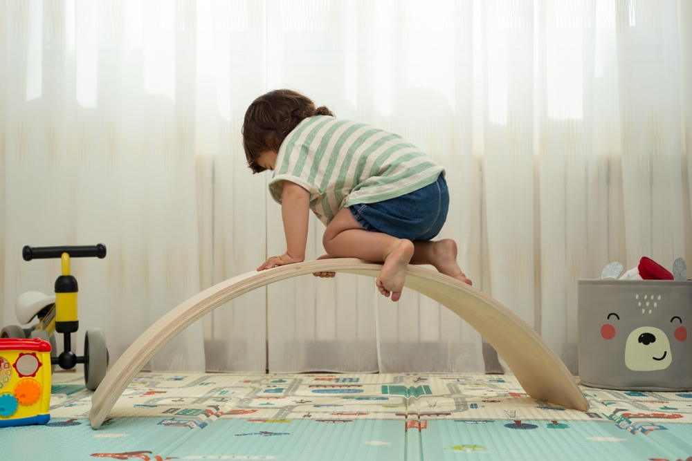 image of toddler climbing on Montessori climbing toys, a wobble board.