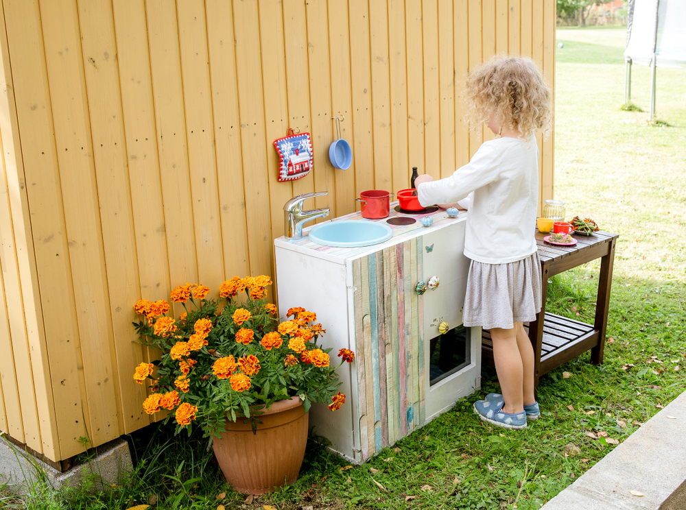 image of child playing at stove on mud kitchen.
