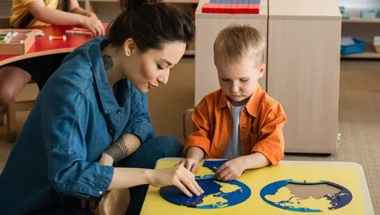 image of a montessori kindergarten teacher showing a child a puzzle map.