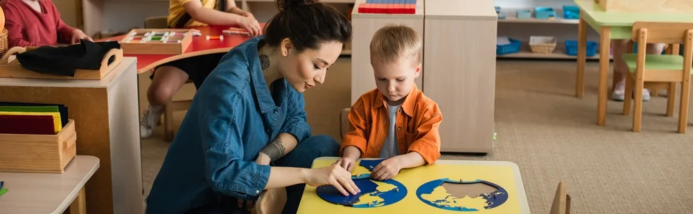 image of a montessori kindergarten teacher showing a child a puzzle map.